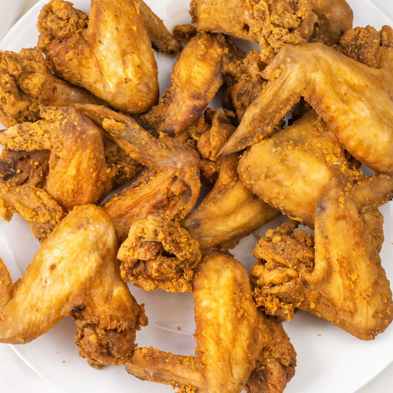Close-up of a pile of crispy, golden-brown fried chicken wings from WingOut Express.